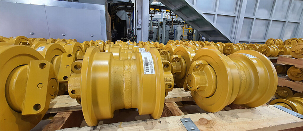 Złote rolki prowadzące ułożone na drewnianych paletach.