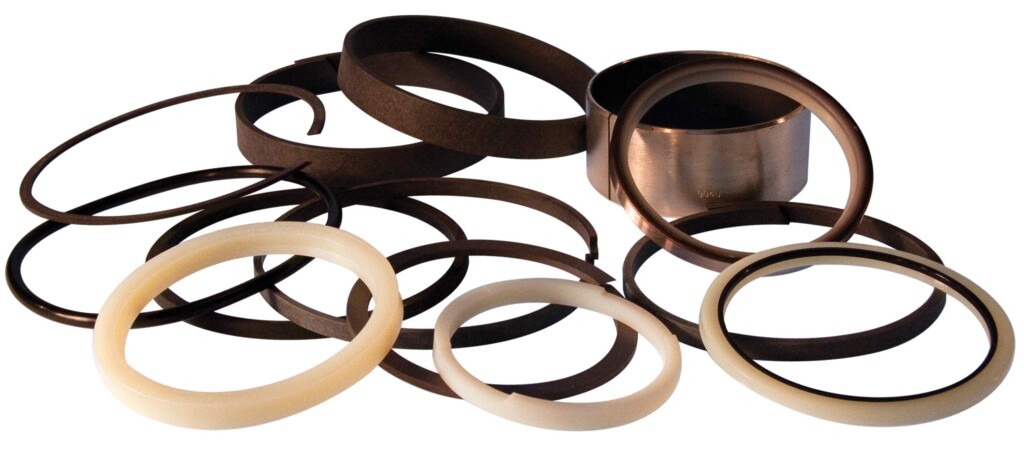 Zestaw pierścieni uszczelniających i tulei w różnych rozmiarach, wykonanych z tworzyw sztucznych i metalu.