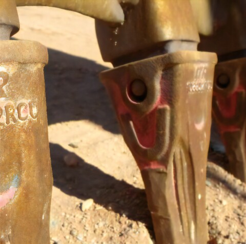 Zbliżenie na zęby koparki, wykonane z metalu.