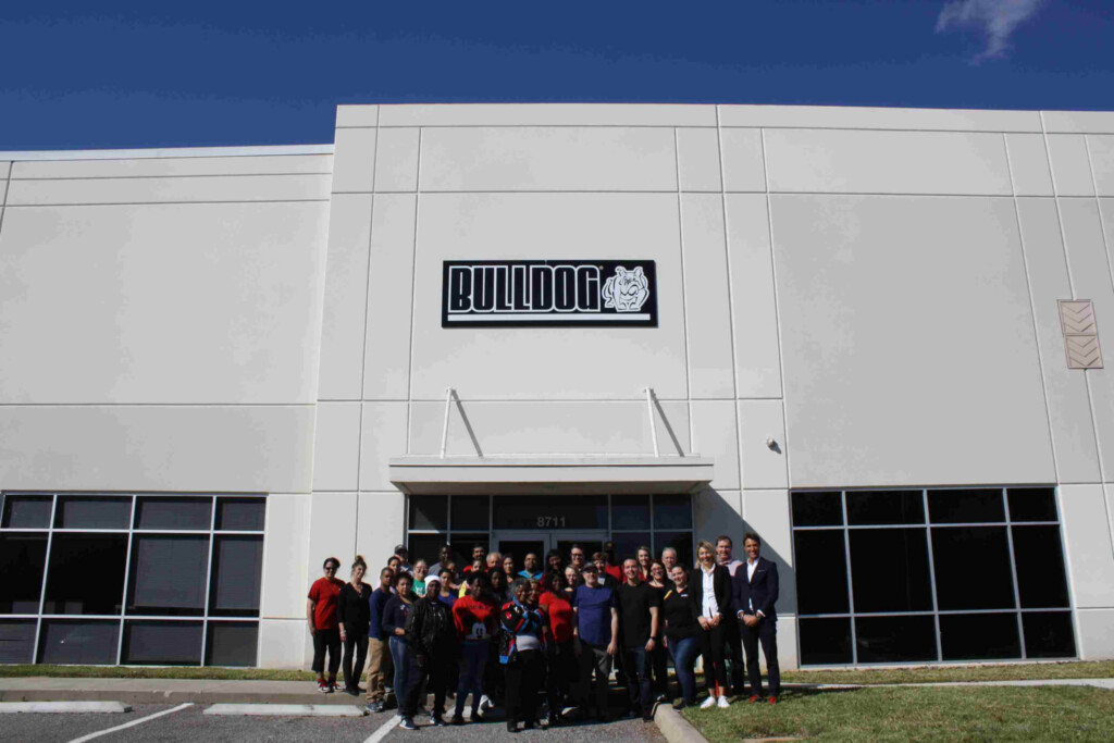 Grupa ludzi stojąca przed budynkiem z logo BULLDOG.