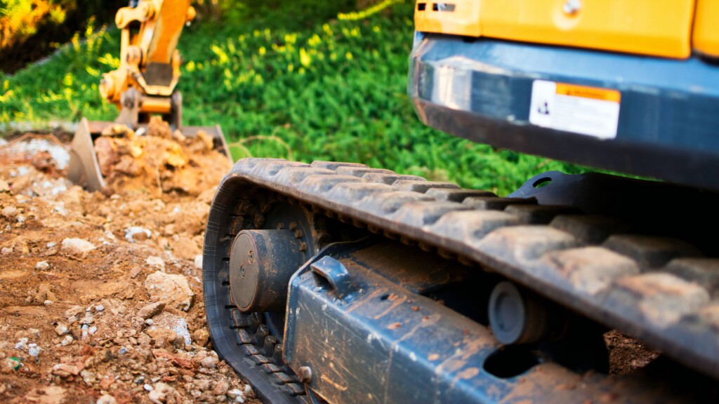 Zbliżenie na gąsienice minikoparki pracującej na terenie budowy