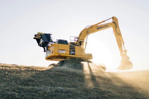 Koparka Komatsu PC240 LC pracująca na wzgórzu o wschodzie słońca.