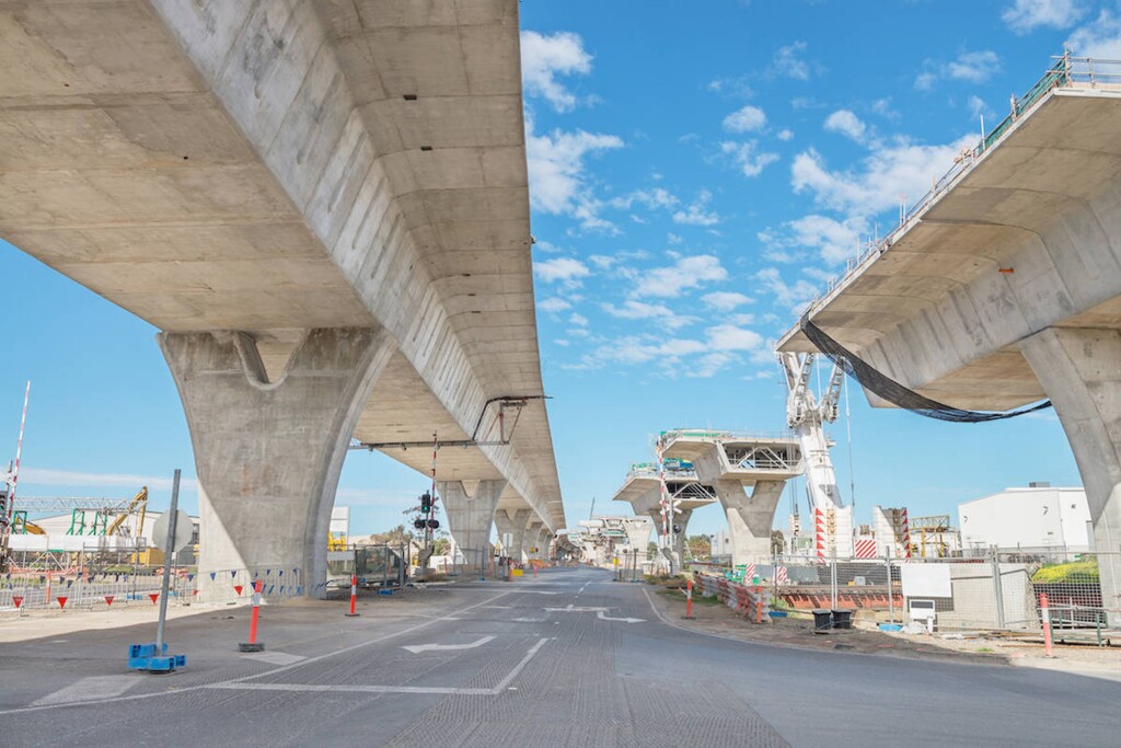 Konstrukcja mostu w trakcie budowy, z widocznymi filarami i częściowo ukończonymi sekcjami mostu.