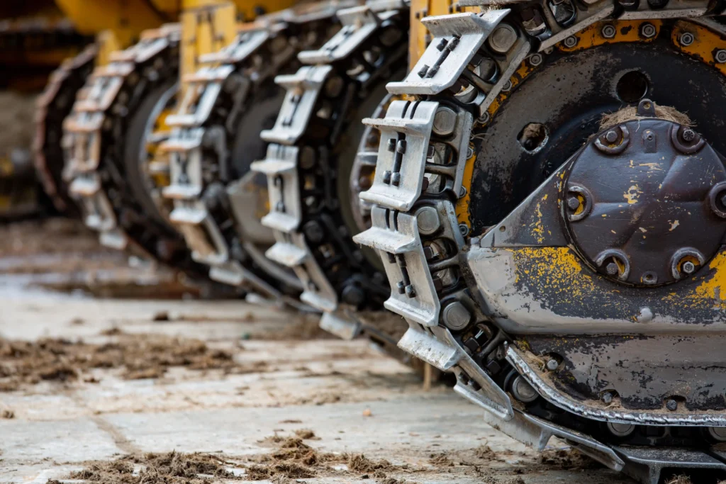 Podwozie gąsienicowe maszyny budowlanej z widocznymi gąsienicami i kołami jezdnymi podczas pracy w trudnych warunkach gruntowych