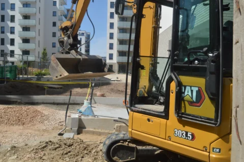 Minikoparka gąsienicowa CAT 303.5 CR wykonująca prace ziemne na placu budowy w terenie miejskim