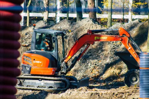 Operator minikoparki podczas wykonywania prac ziemnych na placu budowy